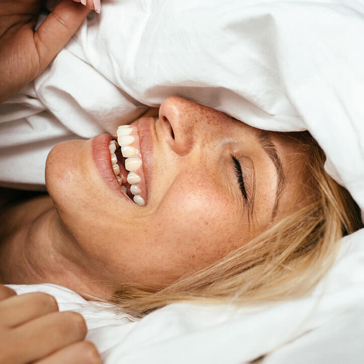 blonde young woman wakes up happy in bed