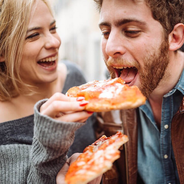 Woman feeds man with pizza