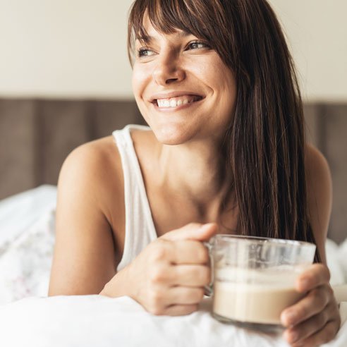 Woman with coffee cup in hand wakes up relaxed