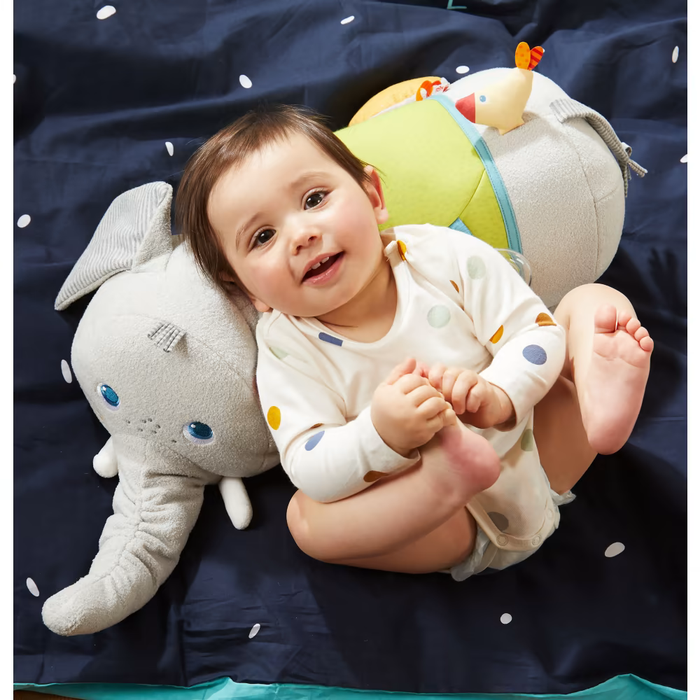 King lies on the elephant cuddly toy from Haba